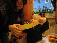 Ein Junge im Krippenalter zeigt einer Frau ein Blatt Papier.